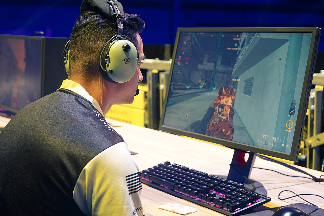 A photo of a player playing a match of an FPS game at an esports stage